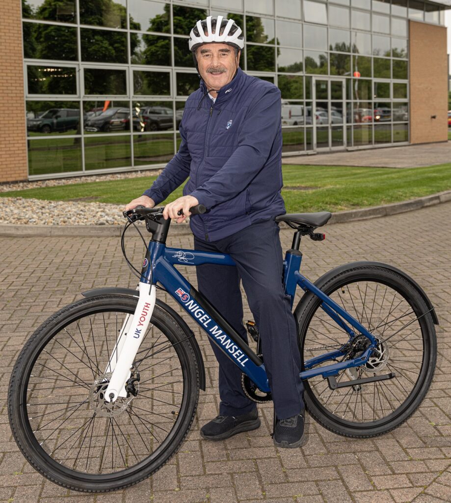 UK Youth president Nigel Mansell stands astride an electric bike, outside the WIlliams Experience Centre.