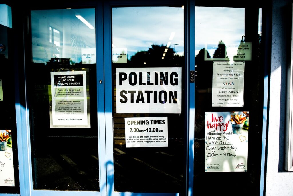 The outside of a polling station, with posters in the window advertising the polling station.